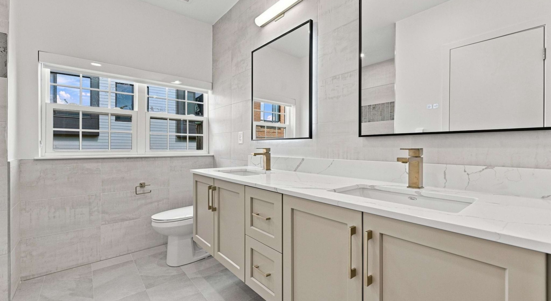 bathroom with sinks mirrors toilet and windows