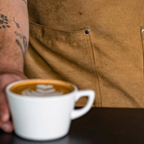 a man with tattoos holding a coffee cup
