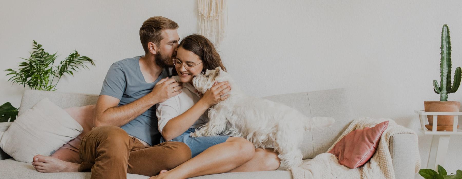 a man and a woman sitting on a couch with a dog